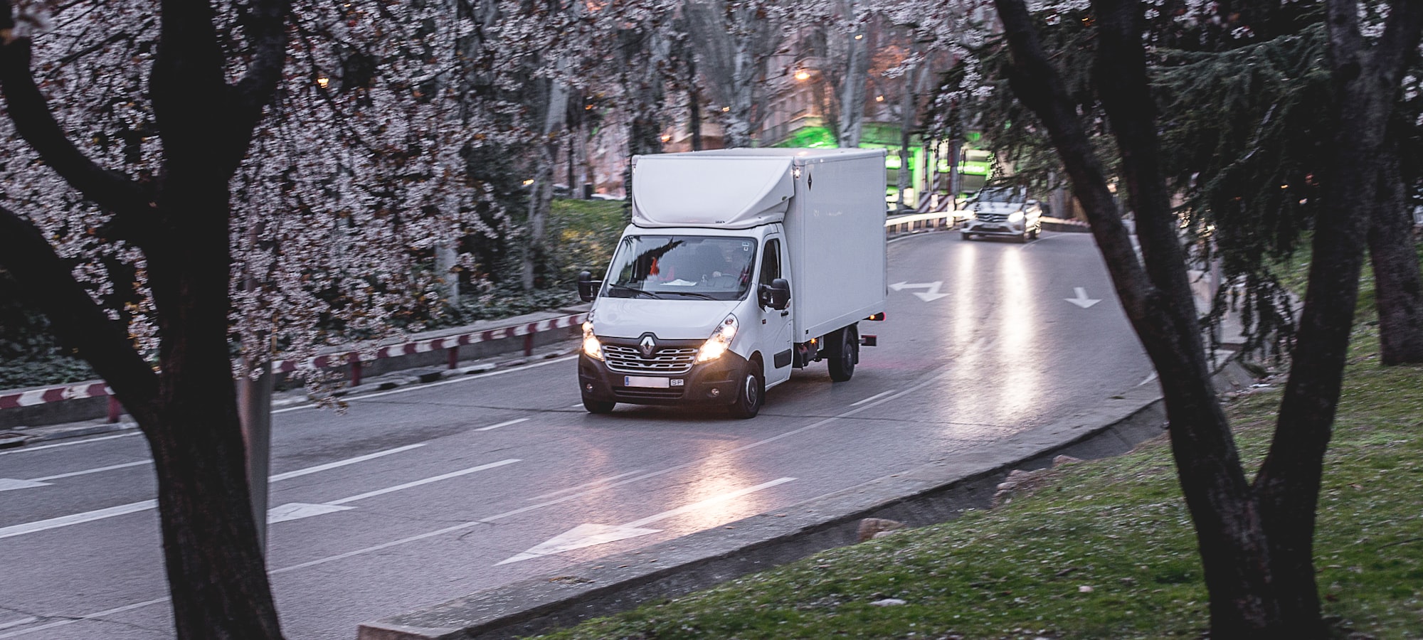 Ein weißer 3,5-Tonnen-Kofferwagen auf einer von Bäumen gesäumten Straße in der Dämmerung